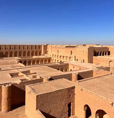 An elevated view shows the extensive, brown clay architecture of the Ksar Ouled Soltane in Tunisia, with a clear blue sky above.
